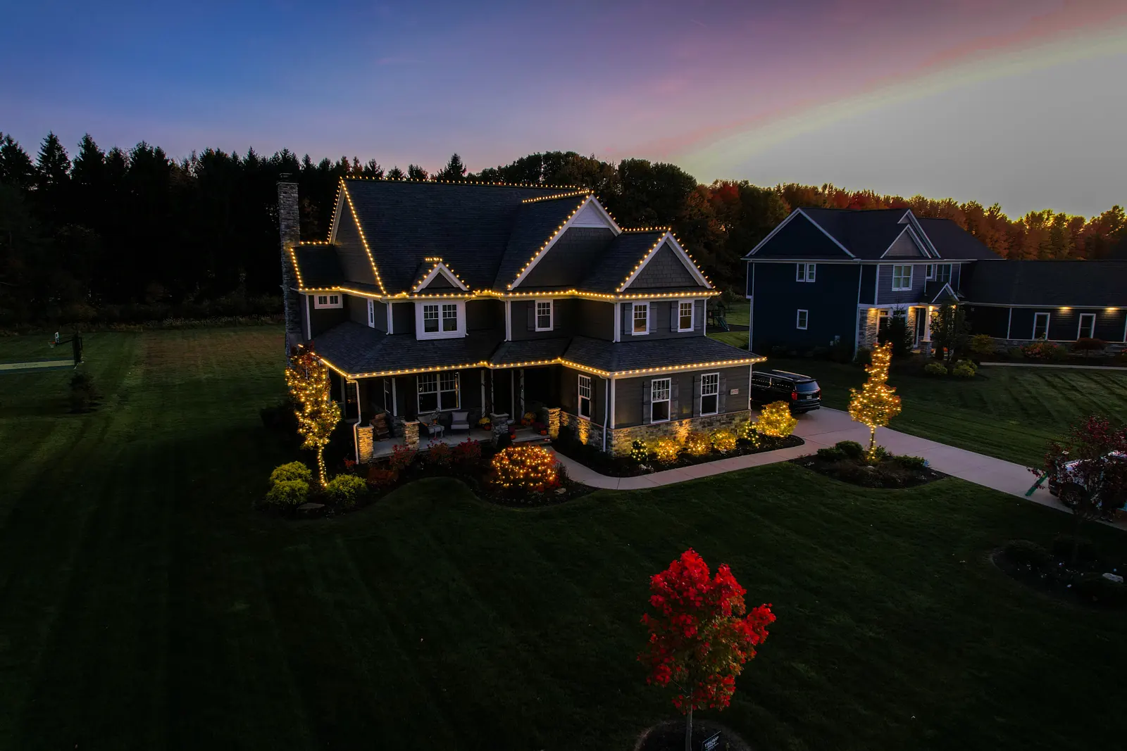 Aerial view of a Northeast Ohio home with warm white Christmas roofline lighting on every peak and gutter line