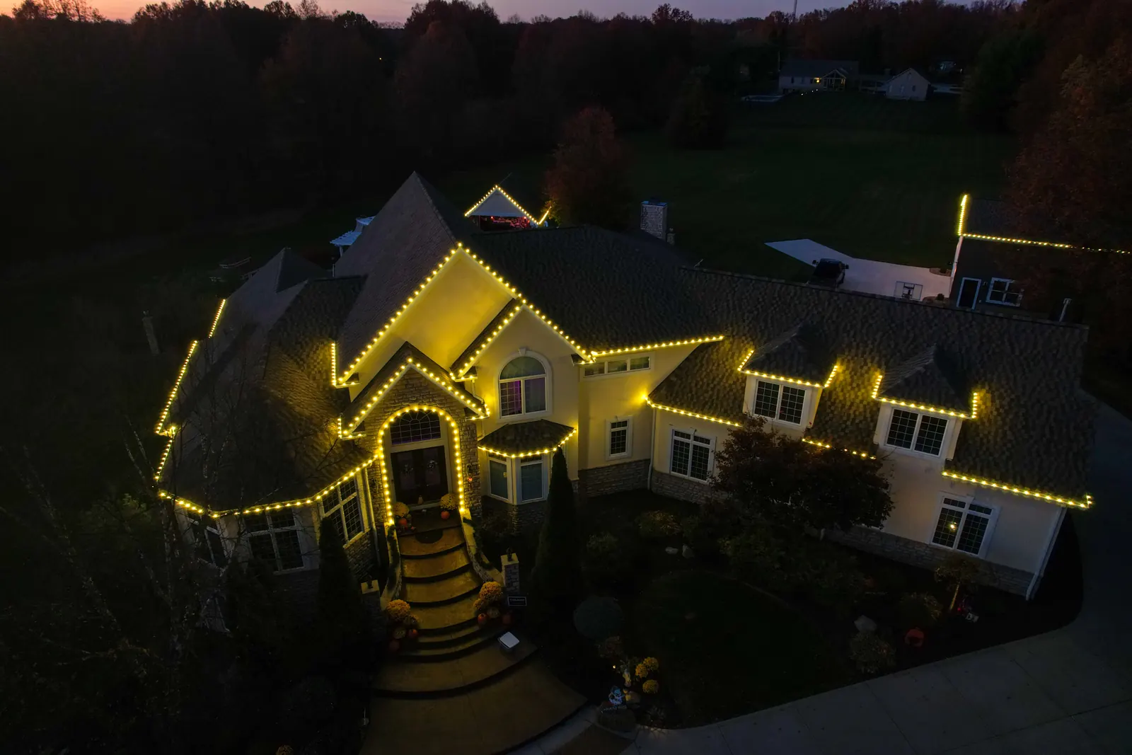 Aerial view of warm white Christmas roofline lighting on a large Ohio home