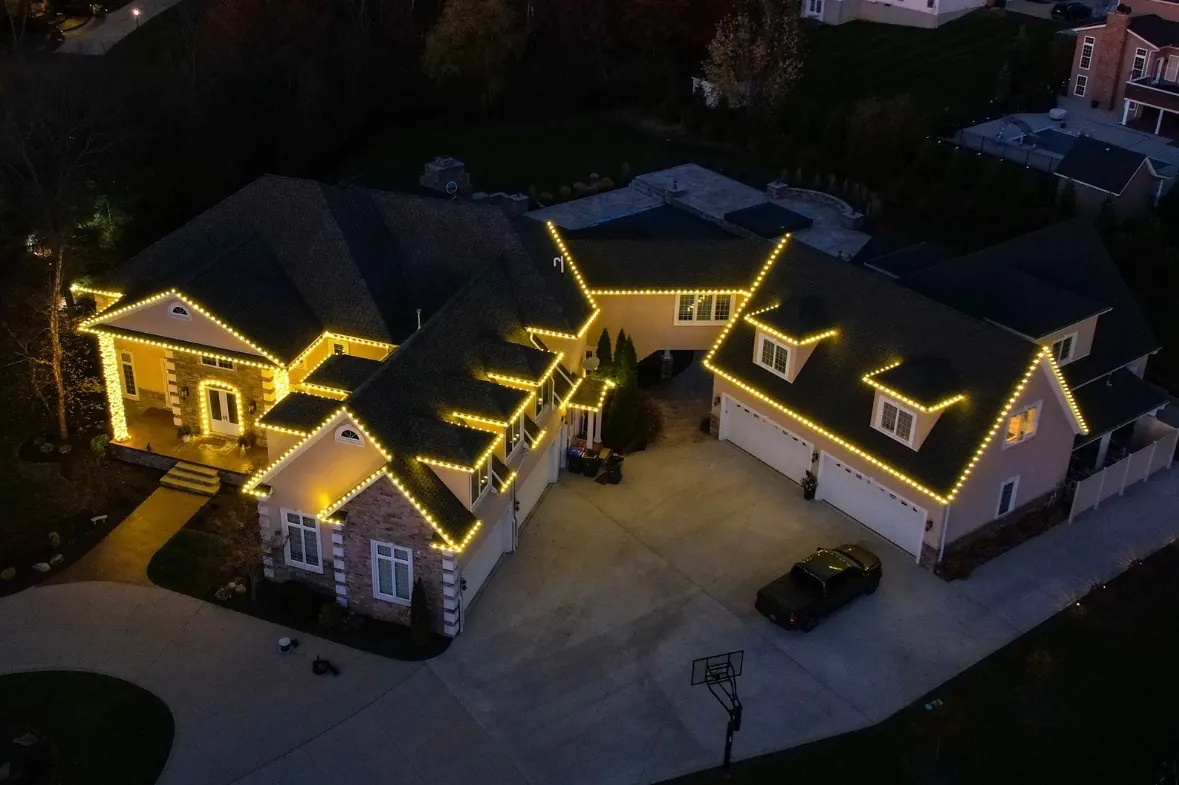 Aerial view of professional Christmas roofline lighting on a luxury home and garage