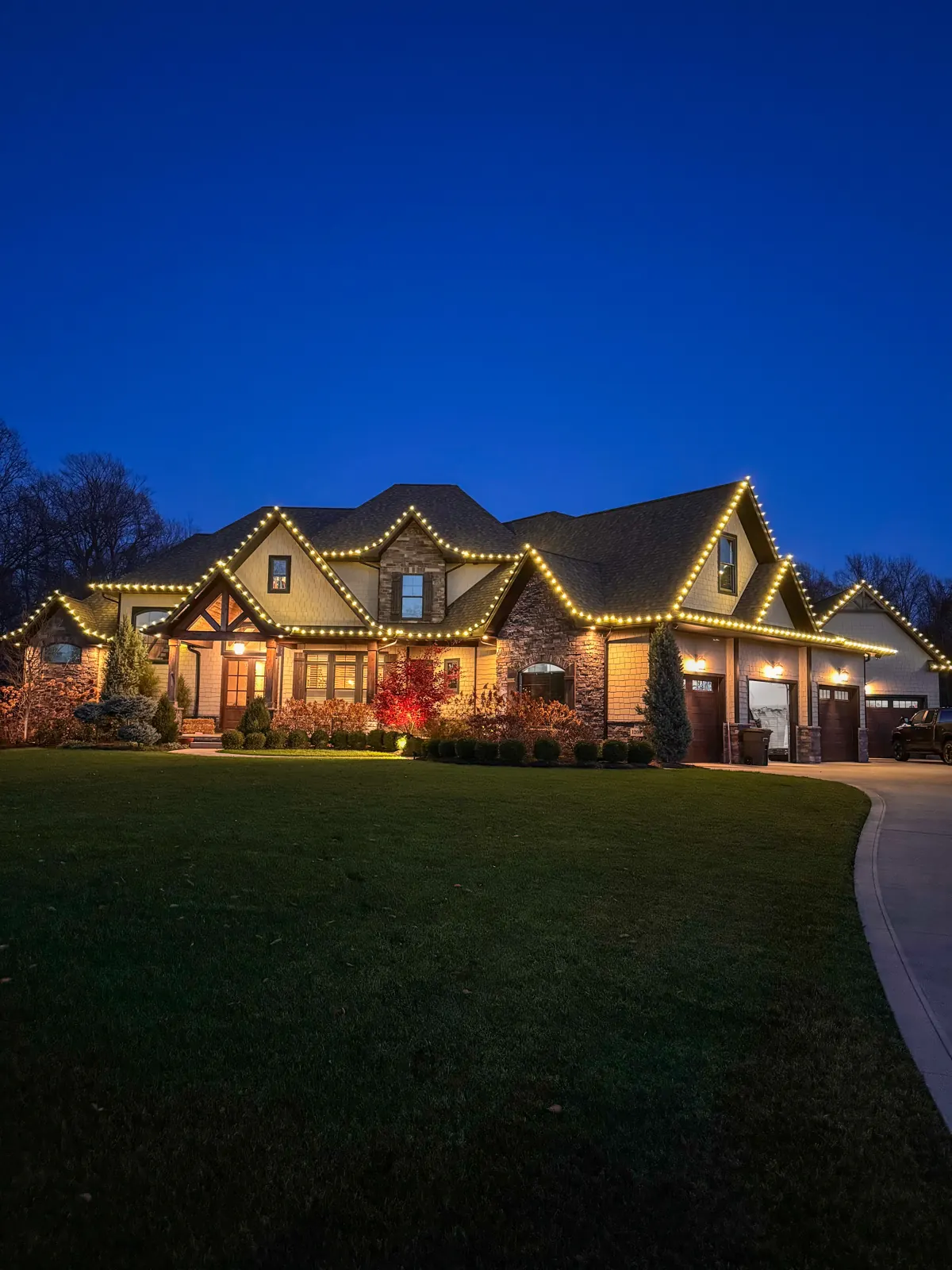 Estate at dusk with warm white Christmas roofline lighting on every peak