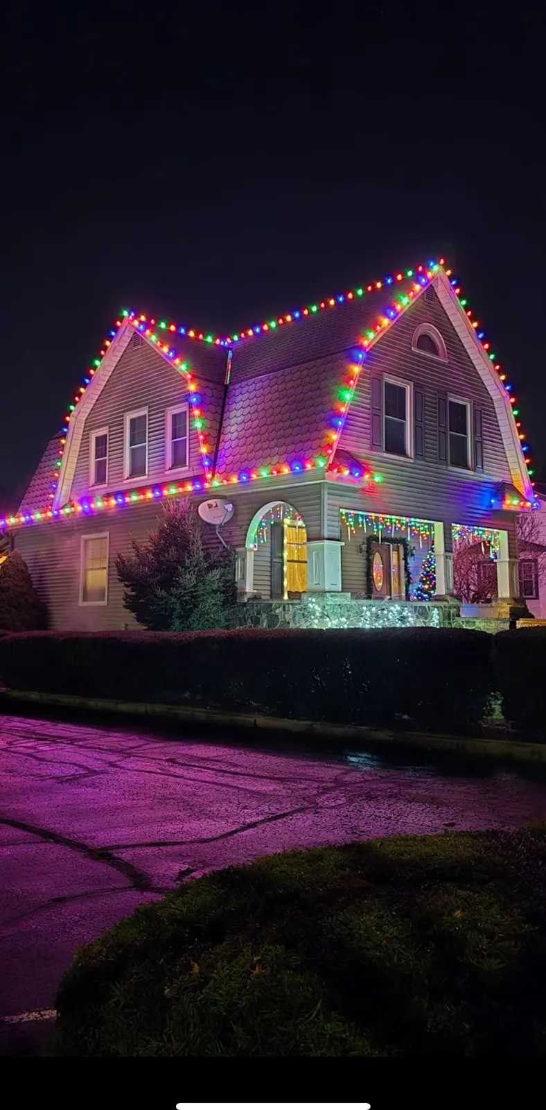 Multicolor Christmas roofline lighting outlining a two-story home