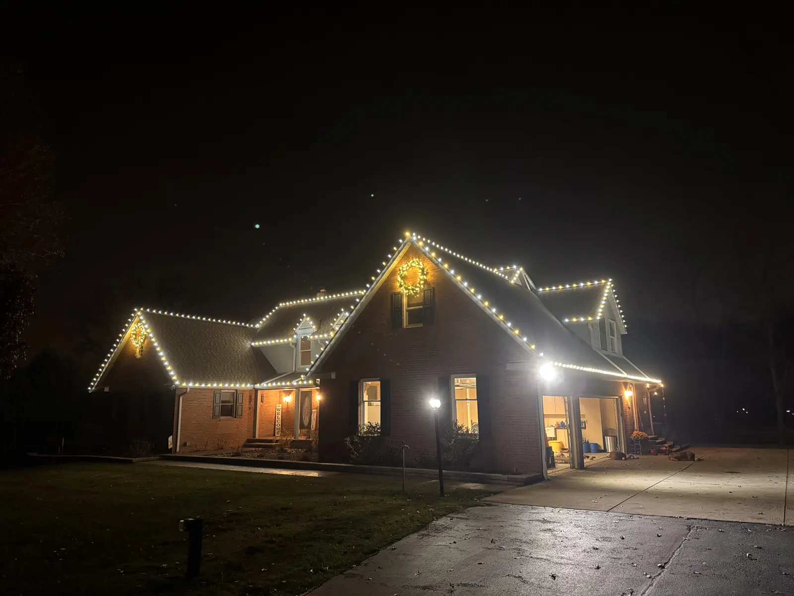 Home with a lit wreath above warm white roofline lighting